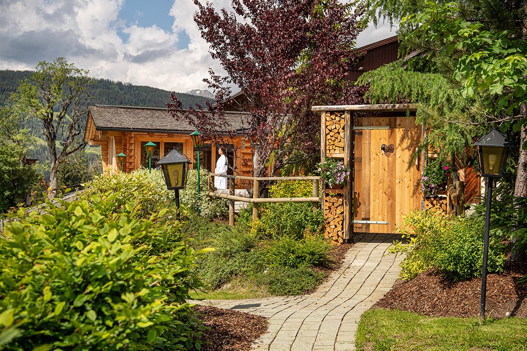 Pathway through garden to wooden sauna hut with heart-shaped door